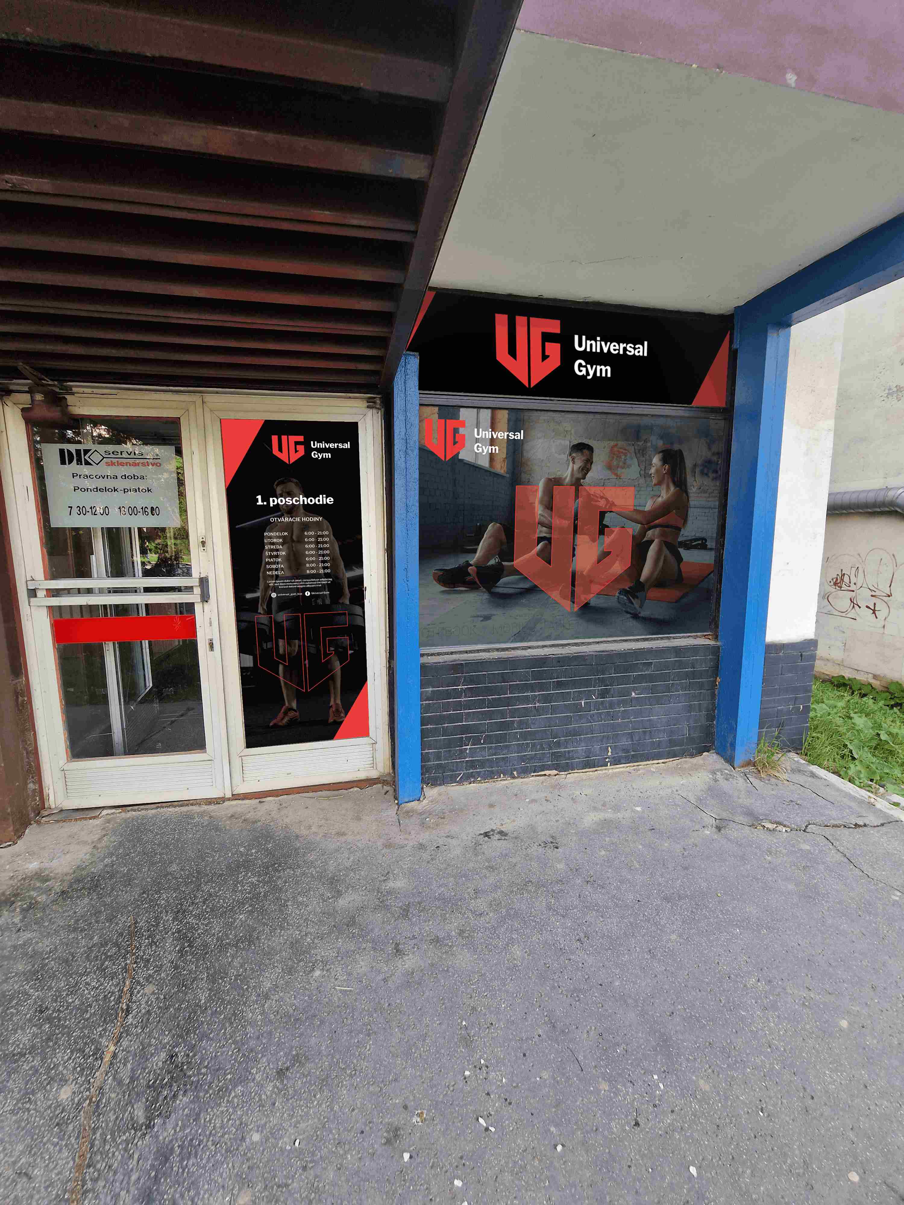 Čierno-červený polep výkladu a vstupných dverí fitness centra Universal Gym s logom, fotografiou cvičiacich žien a prevádzkovými informáciami.