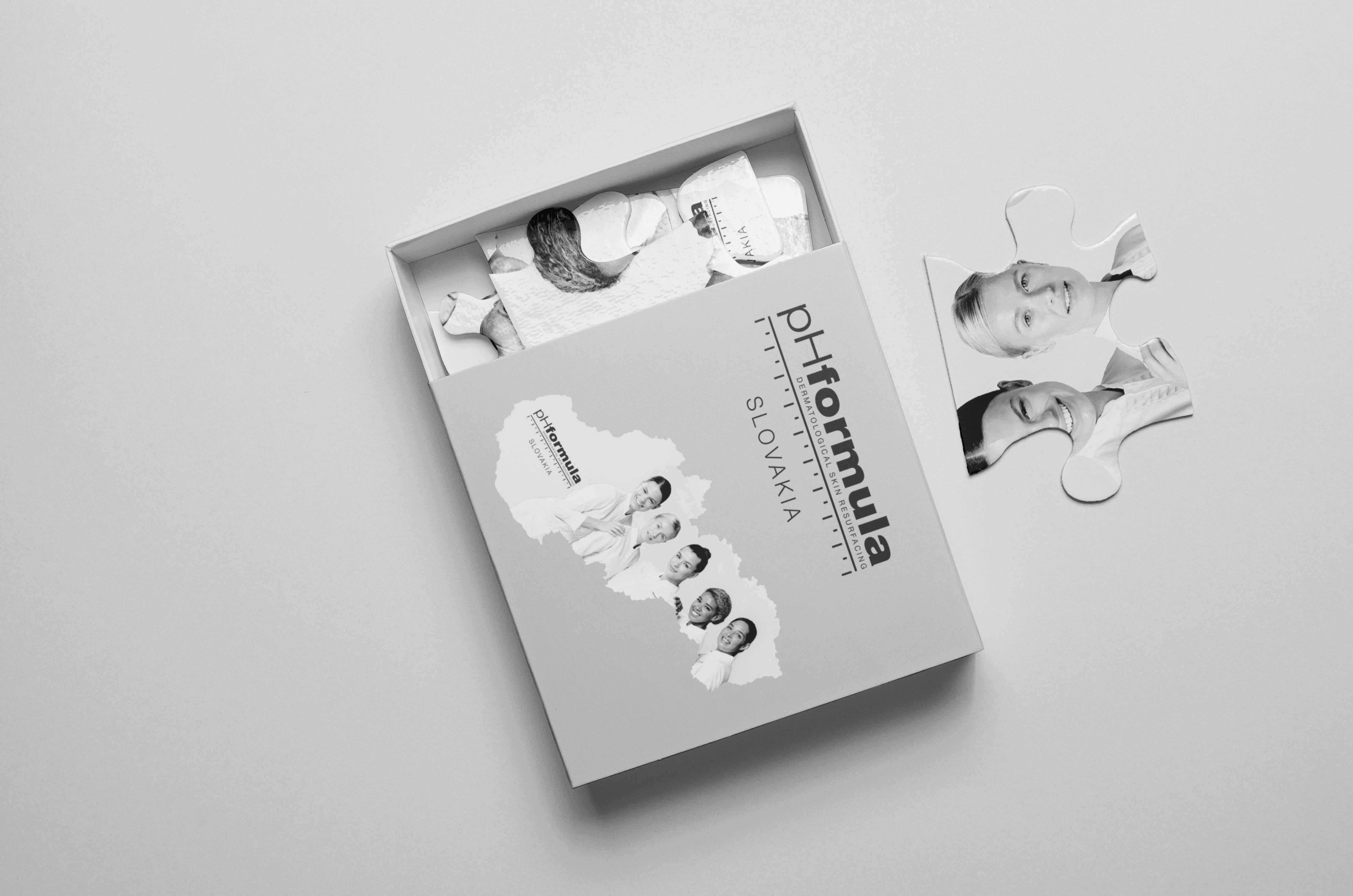 Krabička s logom pHformula Slovakia a dielikmi puzzle s fotografiami tímu.