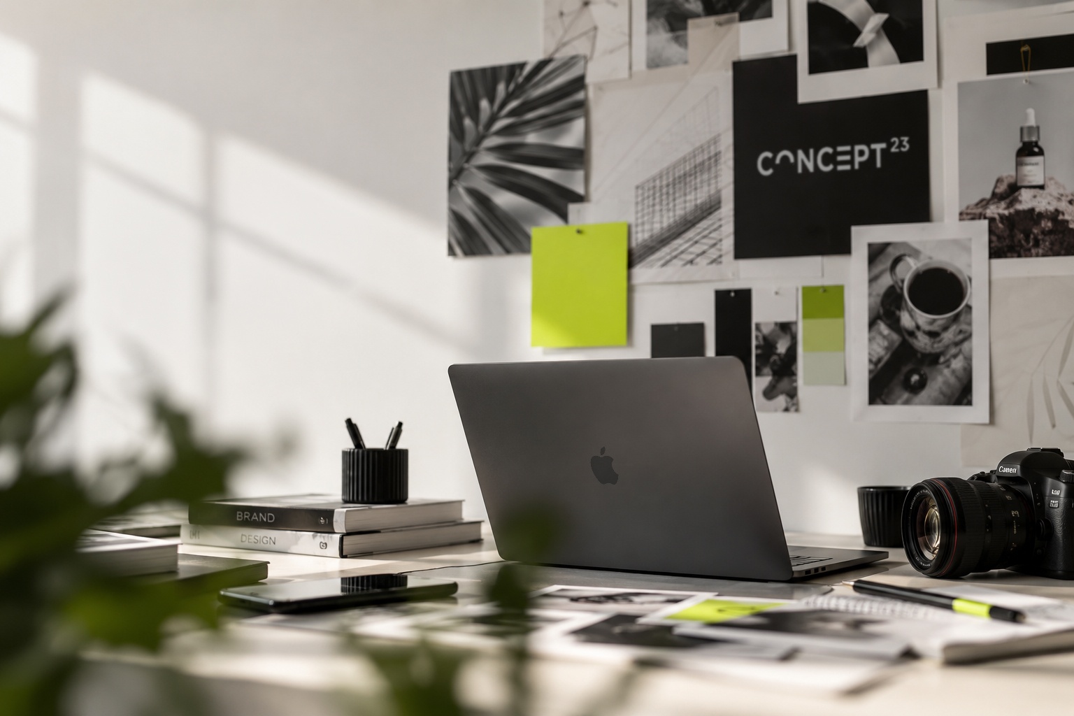 Moderný kreatívny pracovný priestor grafického štúdia concept 23 s notebookom, fotoaparátom, dizajnovými materiálmi a výraznými zelenými detailmi.
