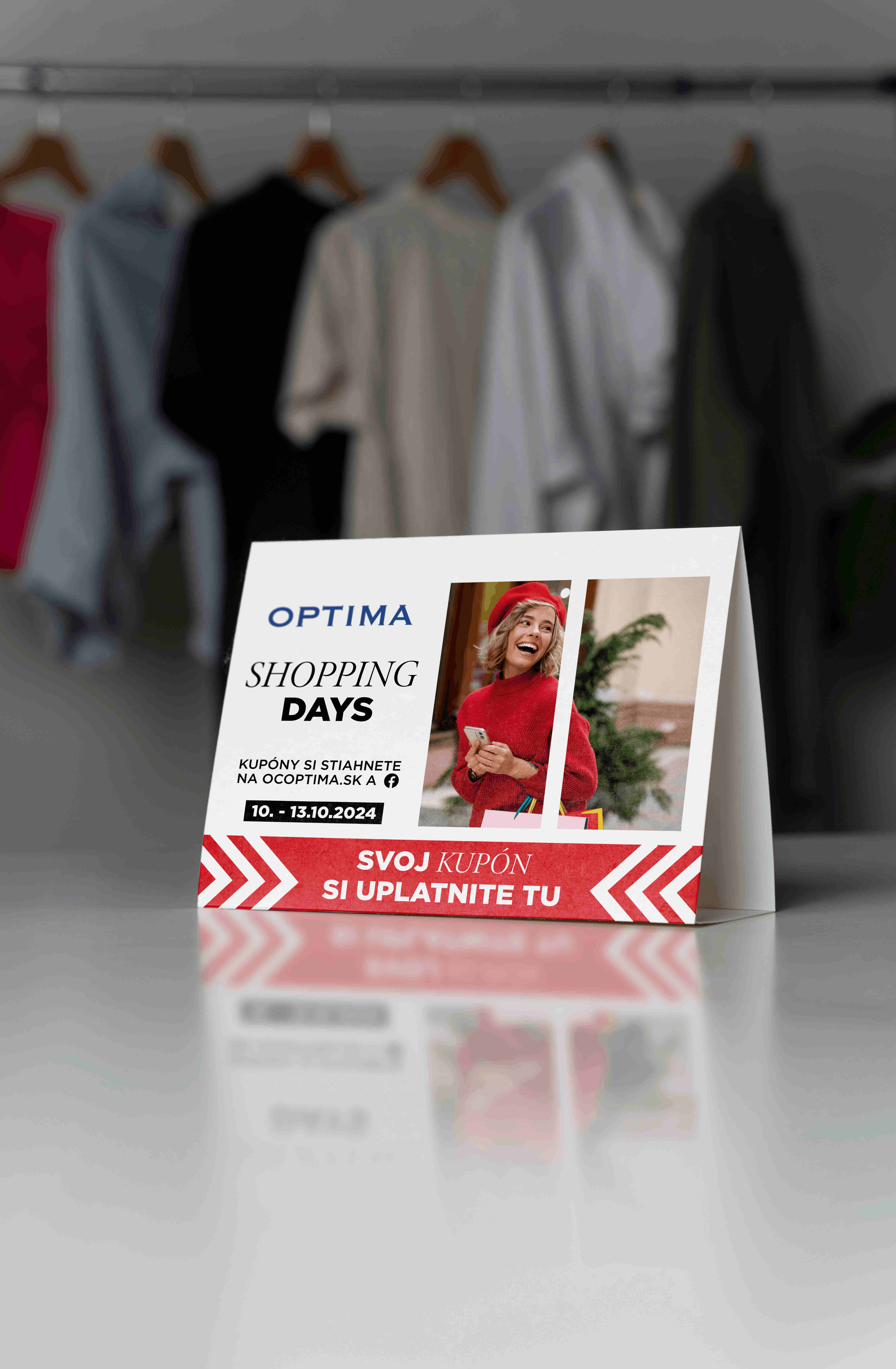 Stolový reklamný stojan OC Optima Shopping Days s fotografiou ženy v červenom oblečení, červenými šípkami a informáciami o nákupných kupónoch.