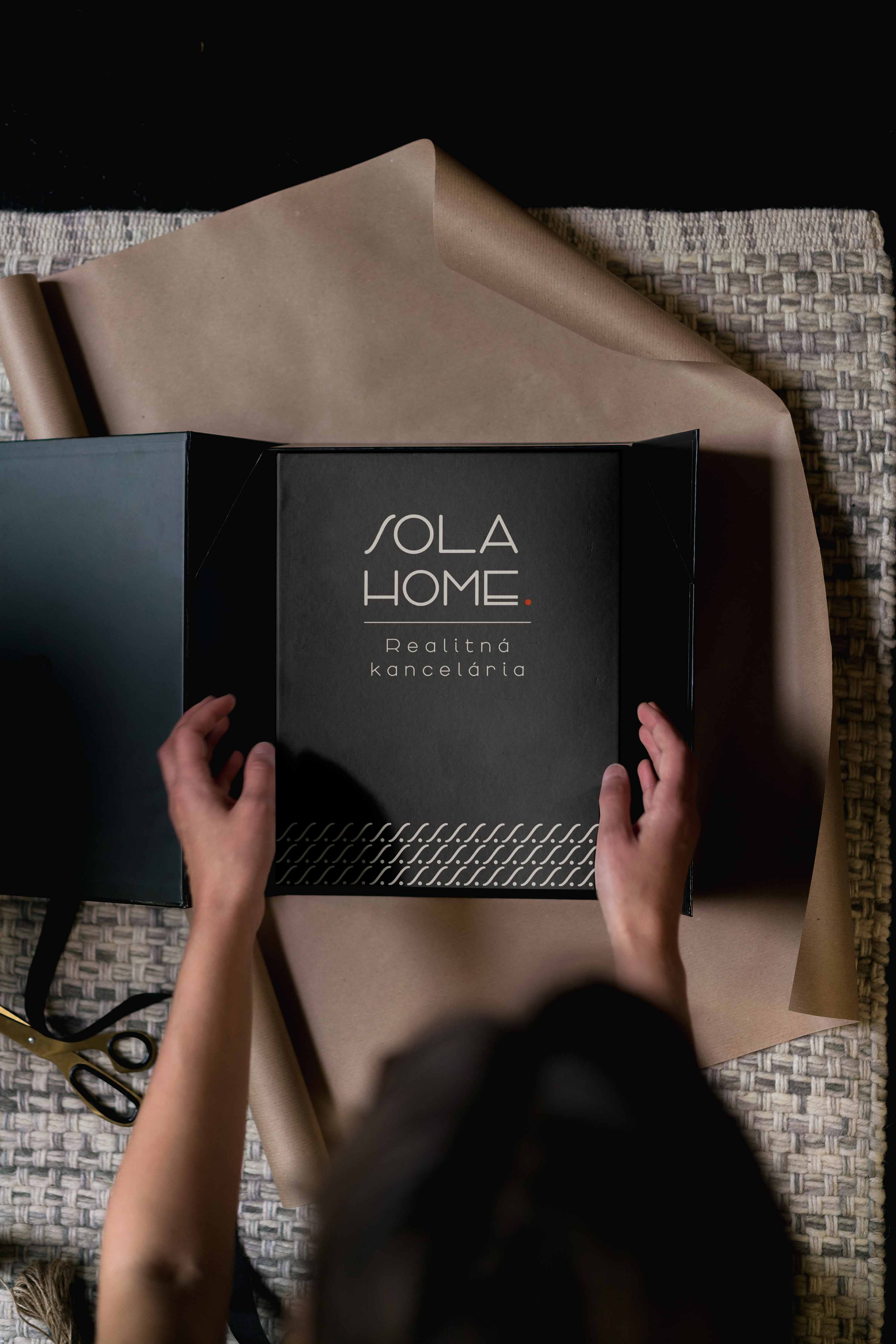 Tmavý folder SOLA HOME so svetlým logom a ozdobným vzorom, vložený do otvorenej darčekovej krabice.