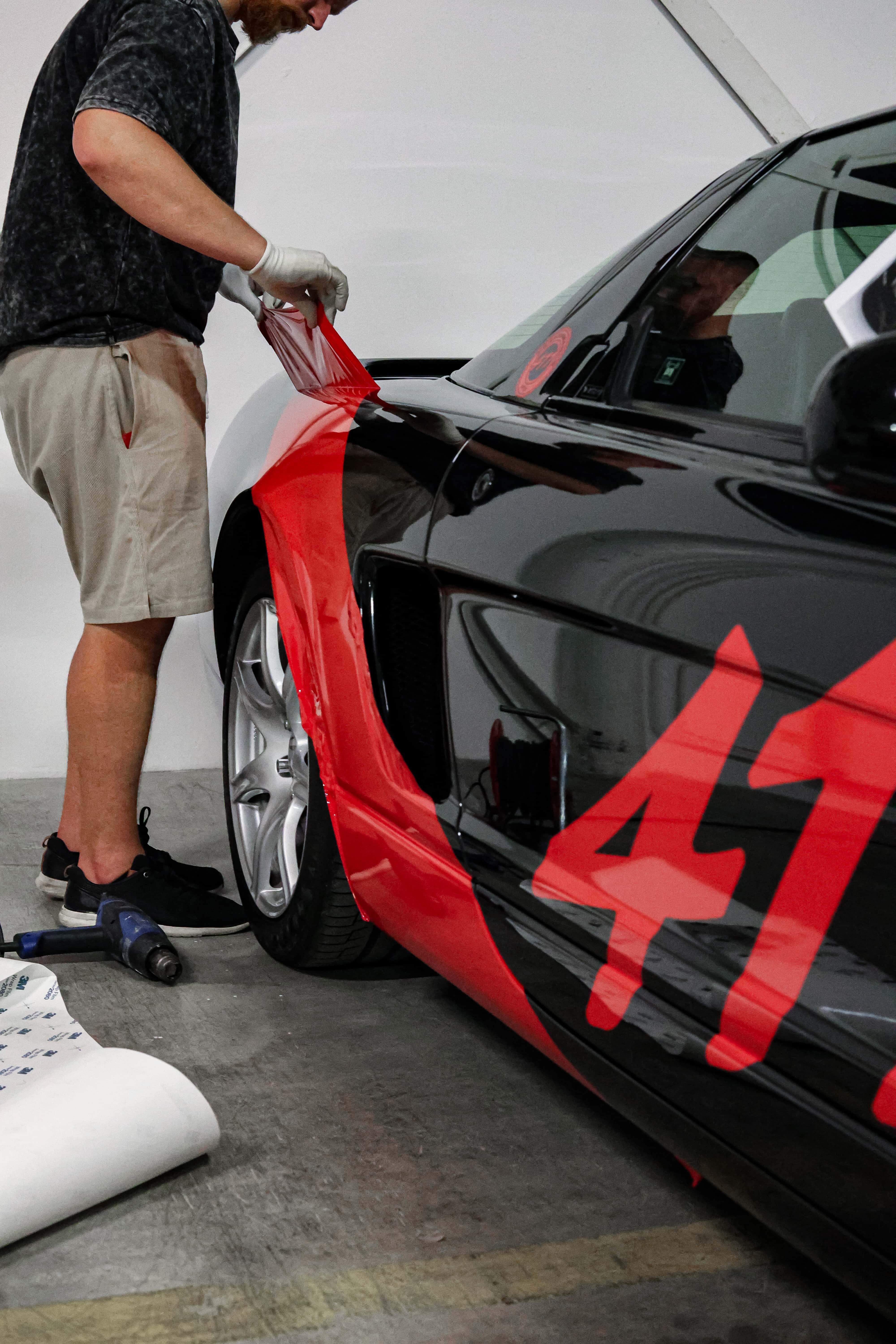 Aplikátor lepí červenú fóliu na auto značky honda.
