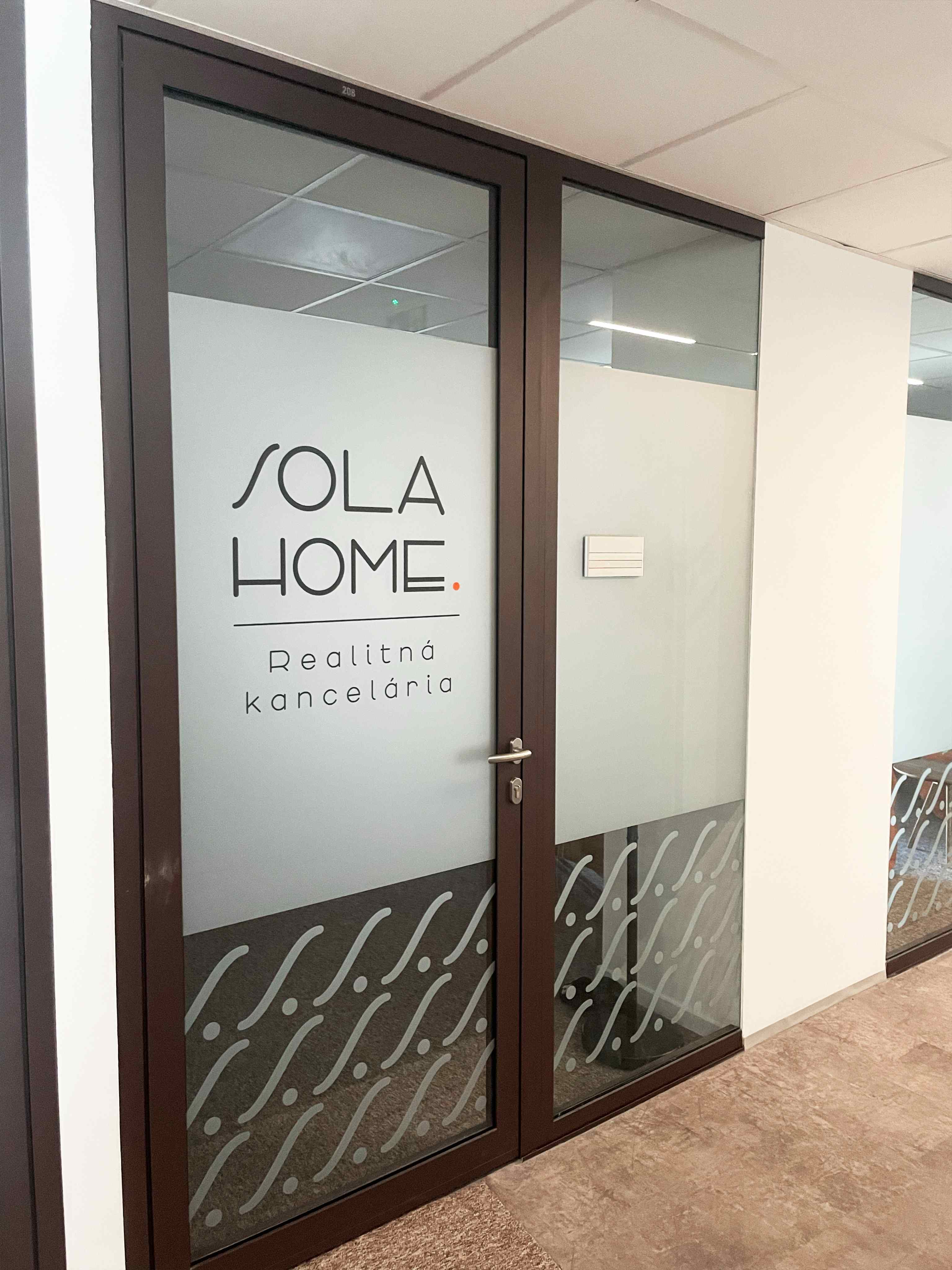 Sklenené vstupné dvere SOLA HOME s logom na matnej fólii a jemným vzorom v spodnej časti.